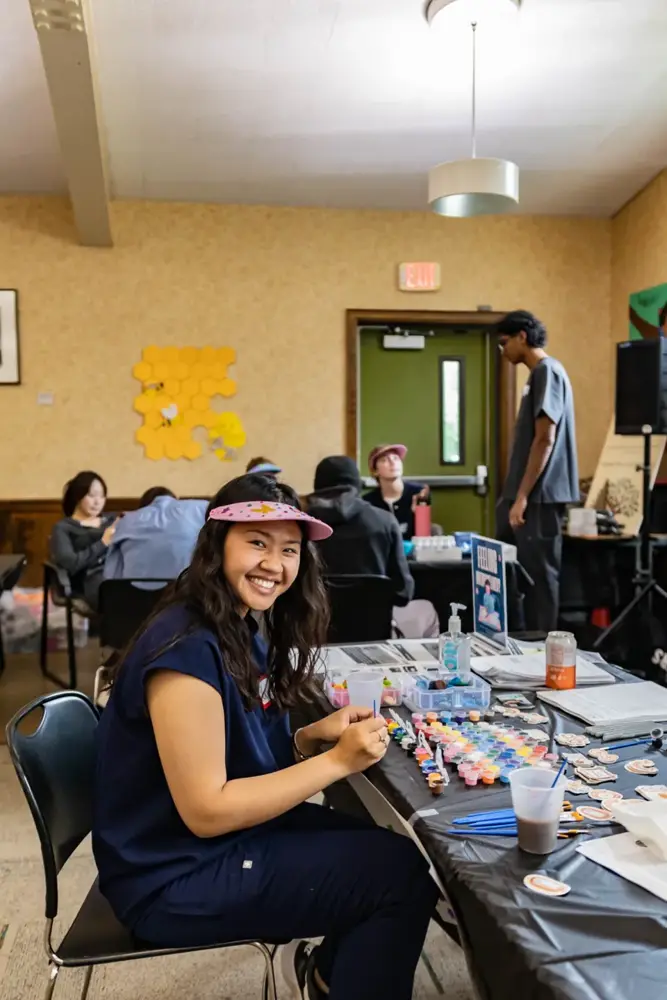 A smiling welcome at a Saturday Clinic exhibit table during the Neighborhood House health fair.