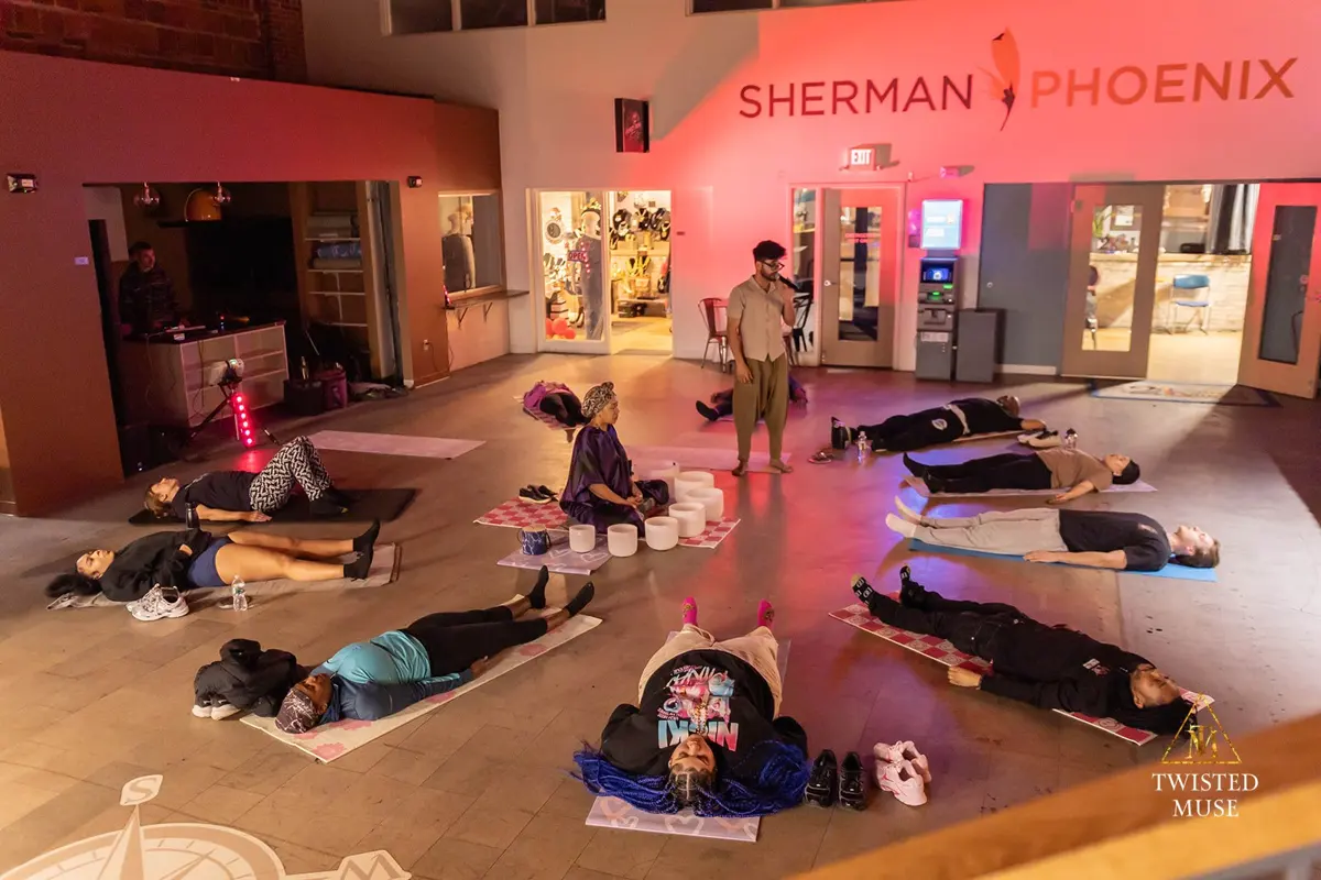 Community members resting on yoga mats around singing bowls during a guided session at Sherman Phoenix